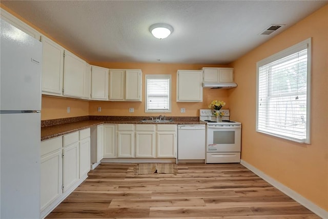 814 E Hayward Ave, Independence, MO 64050 - kitchen with white appliances, a sink, dark countertops, under cabinet range hood, and light wood-type flooring