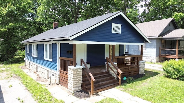 7216 Indiana Ave, Kansas City, MO 64132 - bungalow-style home featuring a porch, roof with shingles, a chimney, and a front lawn