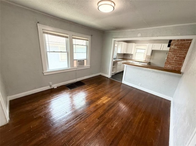 7216 Indiana Ave, Kansas City, MO 64132 - unfurnished living room with dark wood-style flooring, a textured ceiling, baseboards, crown molding, and cooling unit