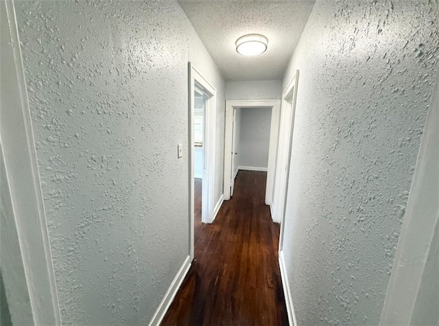 7216 Indiana Ave, Kansas City, MO 64132 - hallway featuring a textured wall, dark wood-style floors, a textured ceiling, and baseboards
