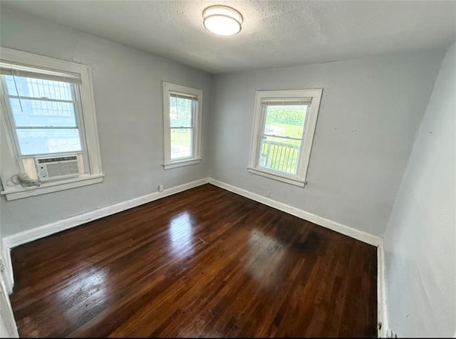 7216 Indiana Ave, Kansas City, MO 64132 - unfurnished room featuring dark wood-style flooring, healthy amount of natural light, baseboards, cooling unit, and a textured ceiling