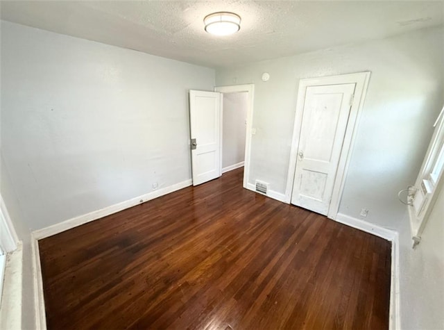 7216 Indiana Ave, Kansas City, MO 64132 - unfurnished bedroom featuring dark wood-style floors, baseboards, and a textured ceiling