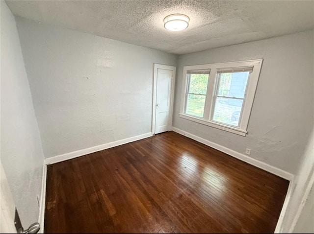 7216 Indiana Ave, Kansas City, MO 64132 - empty room with dark wood-type flooring, baseboards, and a textured ceiling