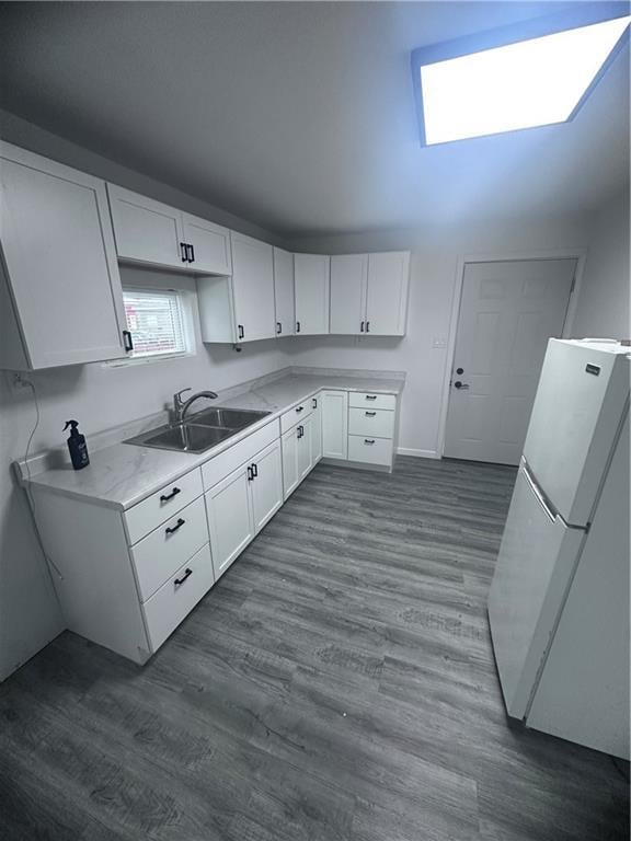 6230 Sherman St, Saint Joseph, MO 64504 - kitchen with freestanding refrigerator, a sink, white cabinets, light countertops, and dark wood-type flooring