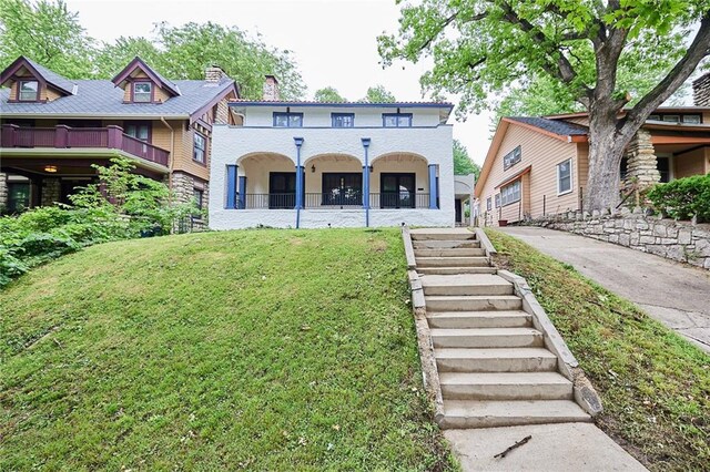 918 W 32nd Ter, Kansas City, MO 64111 - mediterranean / spanish-style home featuring a front lawn, a porch, and stairway