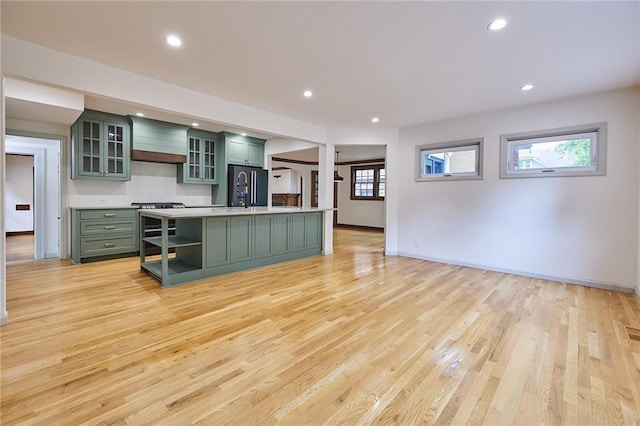 918 W 32nd Ter, Kansas City, MO 64111 - kitchen with green cabinets, fridge, light countertops, light wood-type flooring, and custom range hood