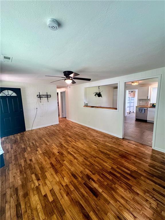 908 N 8th St, Lansing, KS 66043 - unfurnished living room featuring hardwood / wood-style floors, a textured ceiling, and a ceiling fan