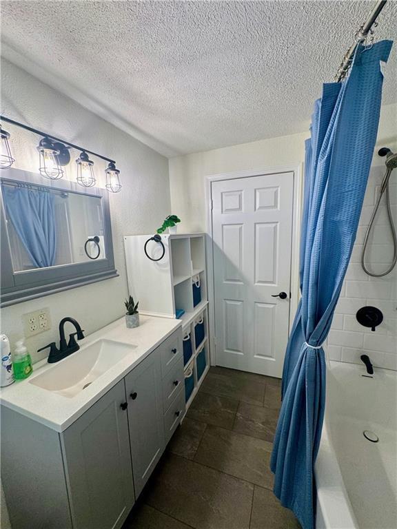 908 N 8th St, Lansing, KS 66043 - bathroom featuring vanity, a textured ceiling, and shower / tub combo with curtain