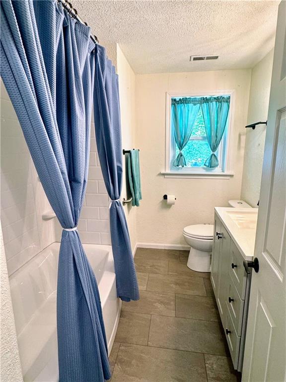 908 N 8th St, Lansing, KS 66043 - bathroom with a textured ceiling, vanity, and shower / bath combo with shower curtain