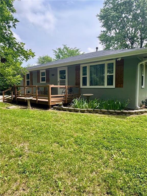 908 N 8th St, Lansing, KS 66043 - view of front of home featuring a front yard, a deck, and stucco siding