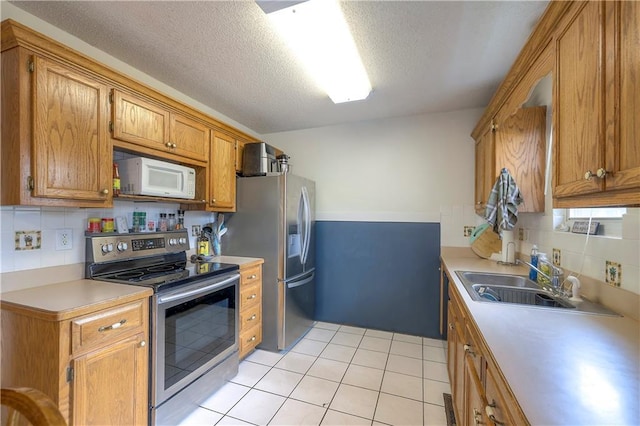 208 N Ohio St, Archie, MO 64725 - kitchen featuring stainless steel appliances, a sink, brown cabinetry, light countertops, and light tile patterned flooring