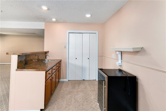 1908 Pine Ridge Dr, Leavenworth, KS 66048 - kitchen featuring brown cabinetry, dark countertops, a peninsula, light carpet, and a textured ceiling