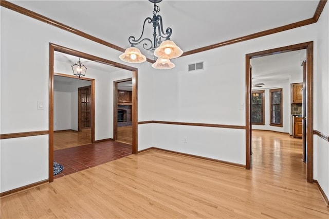 8541 Oakview Dr, Lenexa, KS 66215 - empty room featuring light wood-style flooring, a fireplace with raised hearth, ornamental molding, and a chandelier
