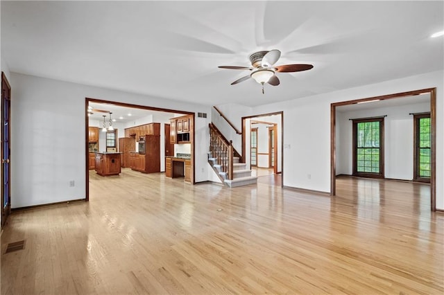 8541 Oakview Dr, Lenexa, KS 66215 - unfurnished living room featuring light wood-type flooring, stairs, and a ceiling fan
