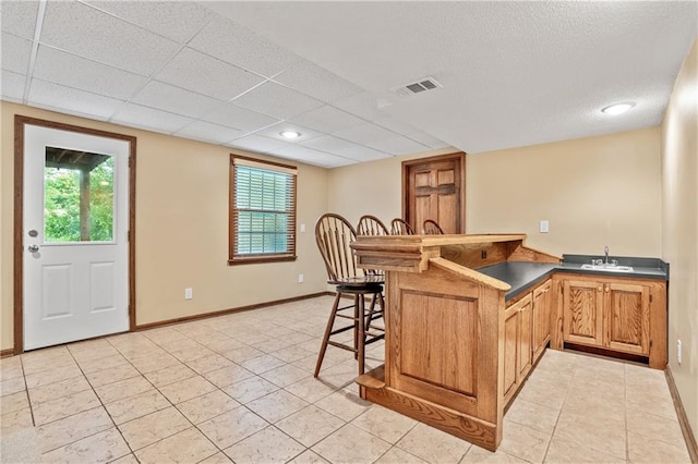 8541 Oakview Dr, Lenexa, KS 66215 - kitchen featuring a kitchen breakfast bar, dark countertops, light tile patterned floors, a peninsula, and healthy amount of natural light