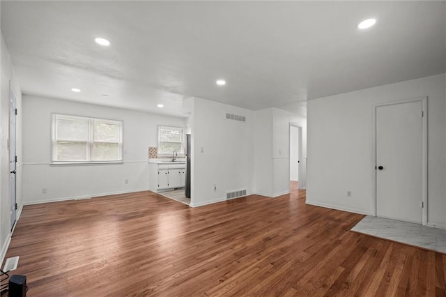 3501 N Delaware St, Independence, MO 64050 - unfurnished living room featuring wood finished floors, recessed lighting, baseboards, and a sink