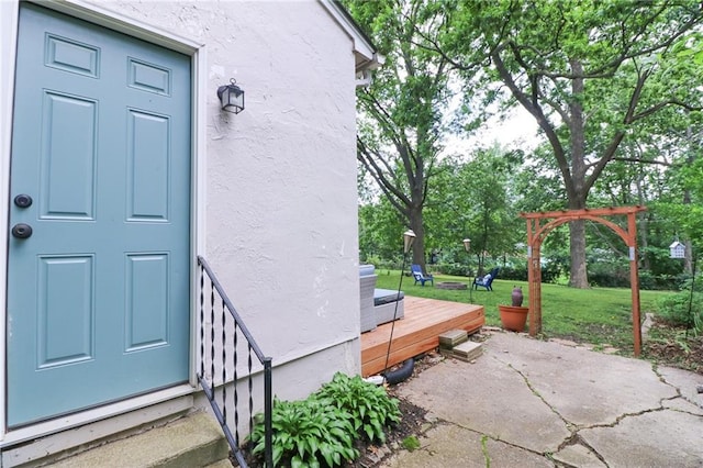 5904 N Howard Ave, Gladstone, MO 64118 - view of exterior entry with stucco siding, a lawn, and a patio