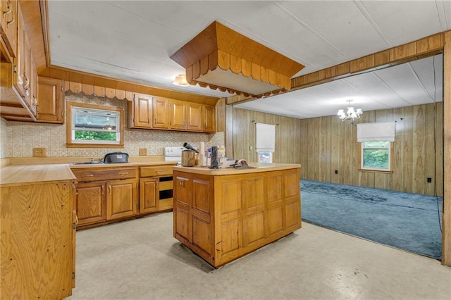 39135 Plum Creek Rd, Osawatomie, KS 66064 - kitchen with light countertops, brown cabinets, a center island, a chandelier, and decorative backsplash