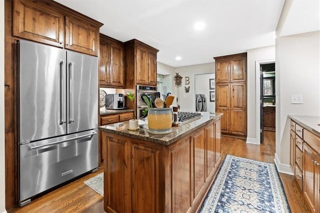 4325 W 112th St, Leawood, KS 66211 - kitchen with appliances with stainless steel finishes, dark wood-type flooring, dark stone counters, a kitchen island, and recessed lighting