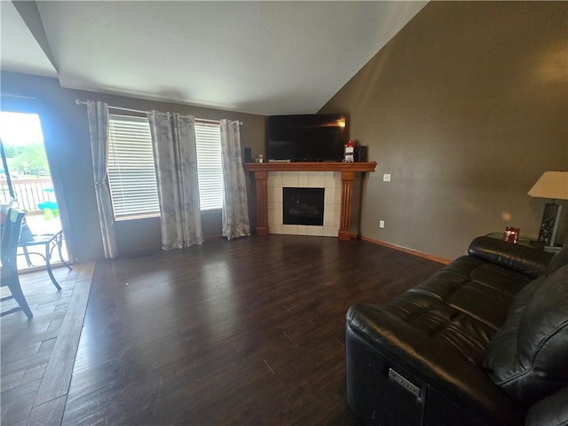 657 SW Tisha Ln, Grain Valley, MO 64029 - living room featuring dark wood-type flooring, a tile fireplace, vaulted ceiling, and baseboards