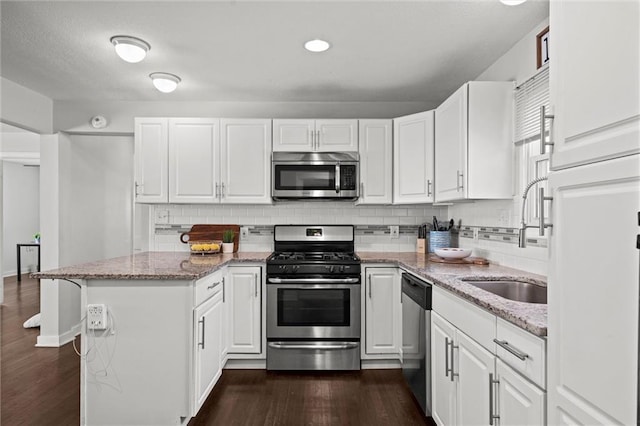 1304 6th Ave, Leavenworth, KS 66048 - kitchen featuring stainless steel appliances, white cabinetry, a peninsula, and decorative backsplash