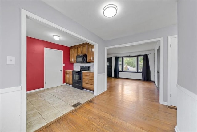 2504 NE 60th St, Gladstone, MO 64118 - kitchen with black appliances, light wood-type flooring, brown cabinets, and light countertops