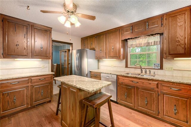 1131 Wildwood St, Leavenworth, KS 66048 - kitchen featuring stainless steel appliances, a sink, a ceiling fan, light wood-type flooring, and brown cabinetry