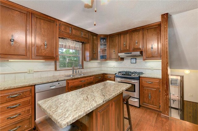 1131 Wildwood St, Leavenworth, KS 66048 - kitchen featuring appliances with stainless steel finishes, a sink, under cabinet range hood, a kitchen bar, and wood finished floors