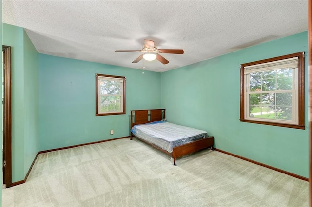 1131 Wildwood St, Leavenworth, KS 66048 - carpeted bedroom with multiple windows, baseboards, a textured ceiling, and ceiling fan