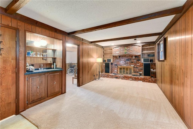 1131 Wildwood St, Leavenworth, KS 66048 - living room with wooden walls, a fireplace, beamed ceiling, carpet, and a textured ceiling
