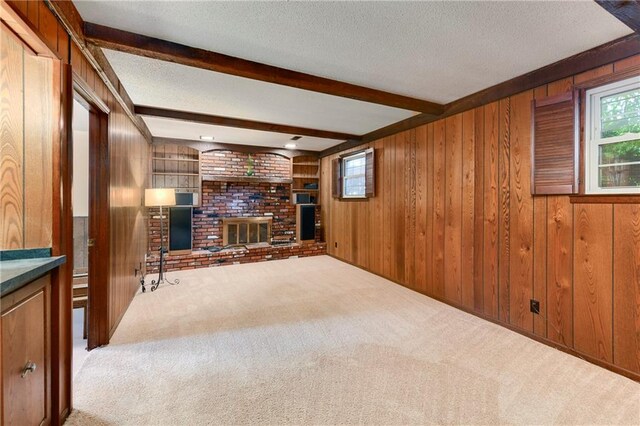 1131 Wildwood St, Leavenworth, KS 66048 - unfurnished living room featuring beam ceiling, carpet floors, wood walls, a fireplace, and a textured ceiling