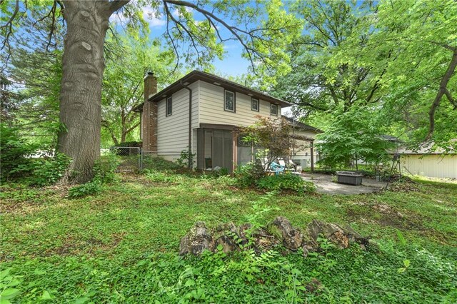 1131 Wildwood St, Leavenworth, KS 66048 - rear view of property with a chimney, a sunroom, a fire pit, and a patio area