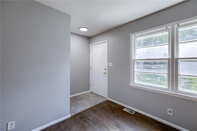 9203 James A Reed Rd, Kansas City, MO 64138 - foyer featuring baseboards, wood finished floors, a textured ceiling, and a textured wall