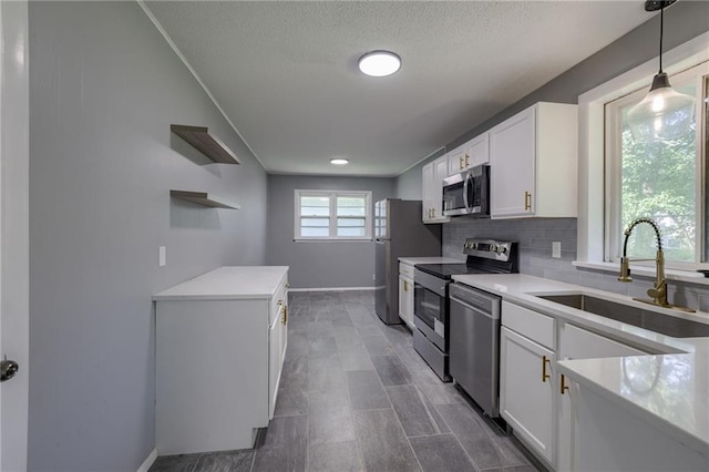 9203 James A Reed Rd, Kansas City, MO 64138 - kitchen featuring stainless steel appliances, a sink, open shelves, white cabinets, and backsplash