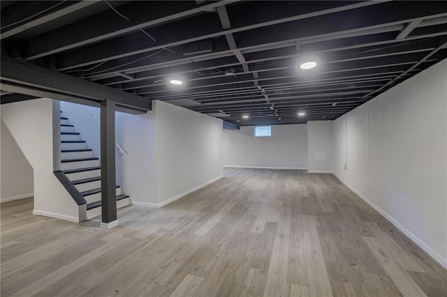 9203 James A Reed Rd, Kansas City, MO 64138 - below grade area with stairs, wood finished floors, and baseboards
