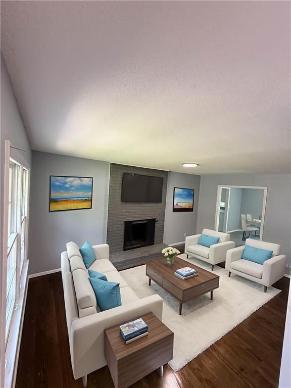 9203 James A Reed Rd, Kansas City, MO 64138 - living area featuring a textured ceiling, wood finished floors, baseboards, and a brick fireplace