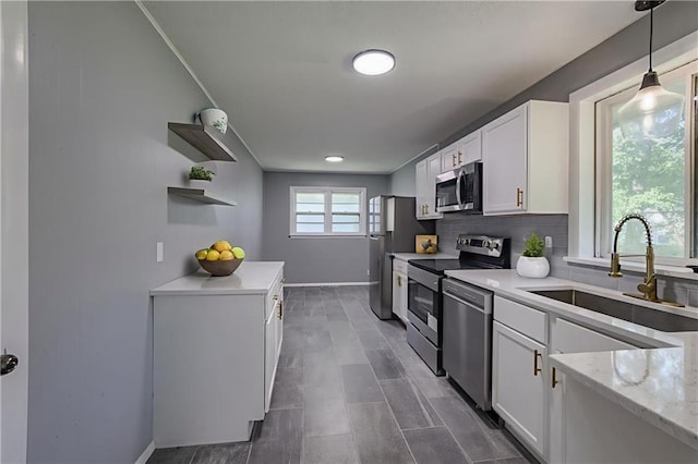 9203 James A Reed Rd, Kansas City, MO 64138 - kitchen with stainless steel appliances, a sink, open shelves, and white cabinets