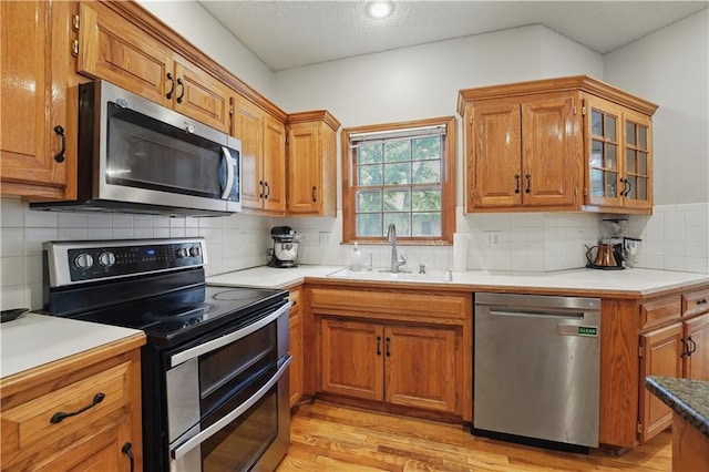 11580 S Skyview Ln, Olathe, KS 66061 - kitchen featuring appliances with stainless steel finishes, a sink, light wood-type flooring, brown cabinetry, and a textured ceiling