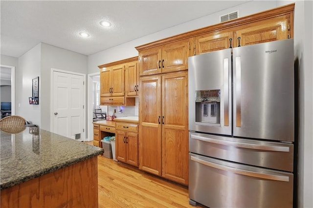 11580 S Skyview Ln, Olathe, KS 66061 - kitchen with stainless steel refrigerator with ice dispenser, light wood-style flooring, recessed lighting, brown cabinets, and dark stone countertops