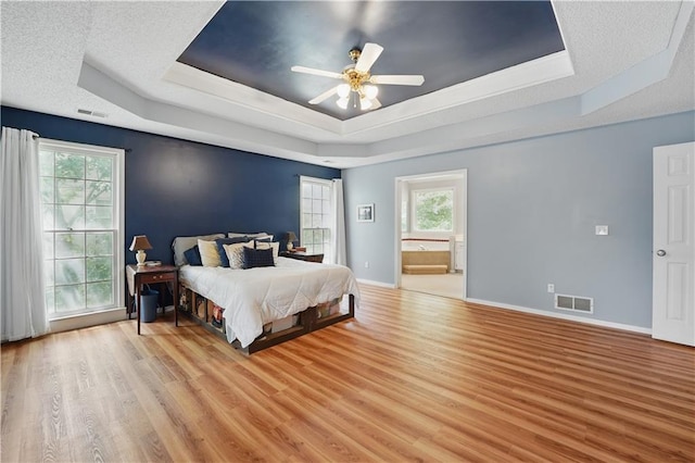 11580 S Skyview Ln, Olathe, KS 66061 - bedroom featuring a raised ceiling, light wood finished floors, ensuite bathroom, ceiling fan, and baseboards