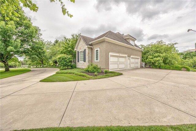 14606 Granada Rd, Leawood, KS 66224 - view of side of home featuring stone siding, concrete driveway, stucco siding, and a garage