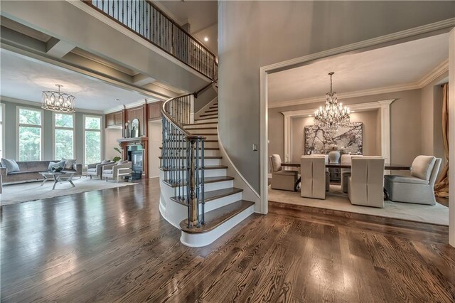 14606 Granada Rd, Leawood, KS 66224 - stairway with a chandelier, wood finished floors, crown molding, and a glass covered fireplace