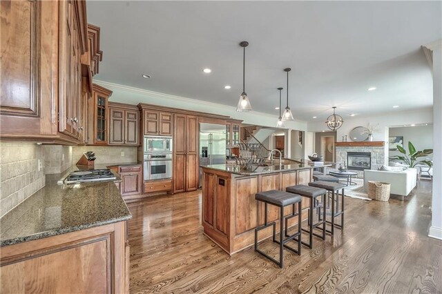14606 Granada Rd, Leawood, KS 66224 - kitchen with built in appliances, brown cabinets, a kitchen breakfast bar, crown molding, and a stone fireplace