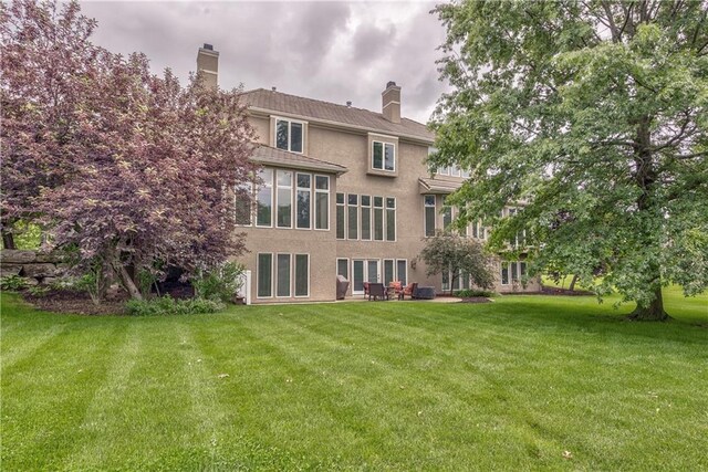 14606 Granada Rd, Leawood, KS 66224 - back of house featuring stucco siding, a lawn, and a chimney