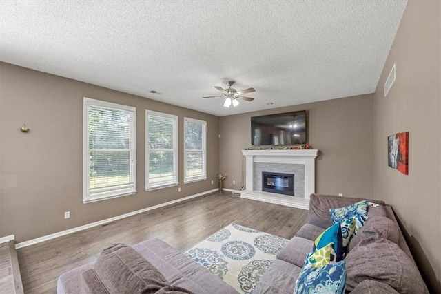 12890 S Greenwood St, Olathe, KS 66062 - living room with a ceiling fan, a glass covered fireplace, wood finished floors, a textured ceiling, and baseboards