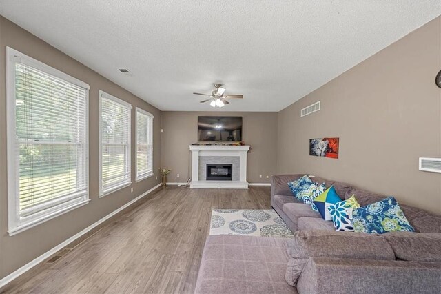 12890 S Greenwood St, Olathe, KS 66062 - living area featuring ceiling fan, wood finished floors, a glass covered fireplace, a textured ceiling, and baseboards
