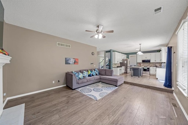 12890 S Greenwood St, Olathe, KS 66062 - living room with ceiling fan, light wood-style floors, baseboards, and a textured ceiling