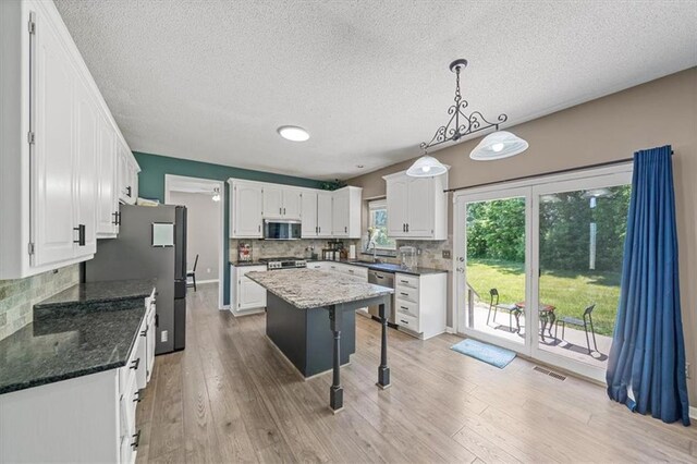 12890 S Greenwood St, Olathe, KS 66062 - kitchen featuring stainless steel appliances, backsplash, white cabinetry, light wood-style flooring, and a textured ceiling