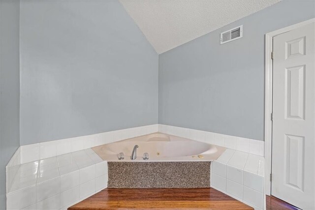12890 S Greenwood St, Olathe, KS 66062 - bathroom with a jetted tub, lofted ceiling, and wood finished floors