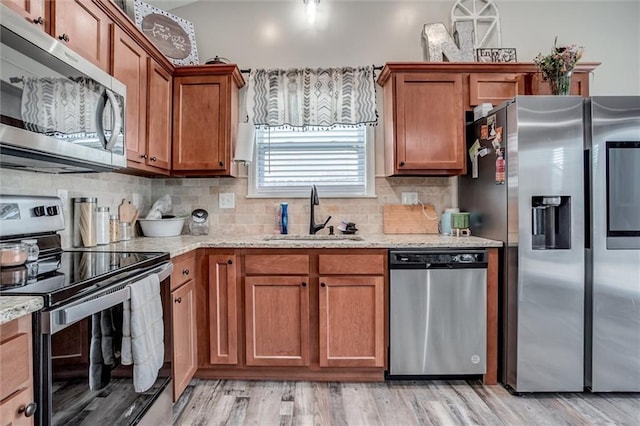1609 Bluestem Dr, Ottawa, KS 66067 - kitchen featuring appliances with stainless steel finishes, a sink, brown cabinets, backsplash, and light stone counters